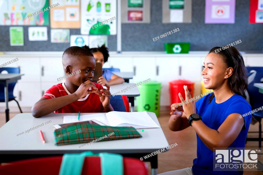 Stock Photo: African american female teacher and boy talking in hand sign language at elementary school.