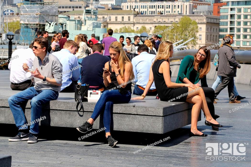 Stock Photo: Office workers and tourists enjoy warm sunshine in The Scoop and near Tower Bridge as temperatures are likely to reach 19 degrees celsius in the capital.