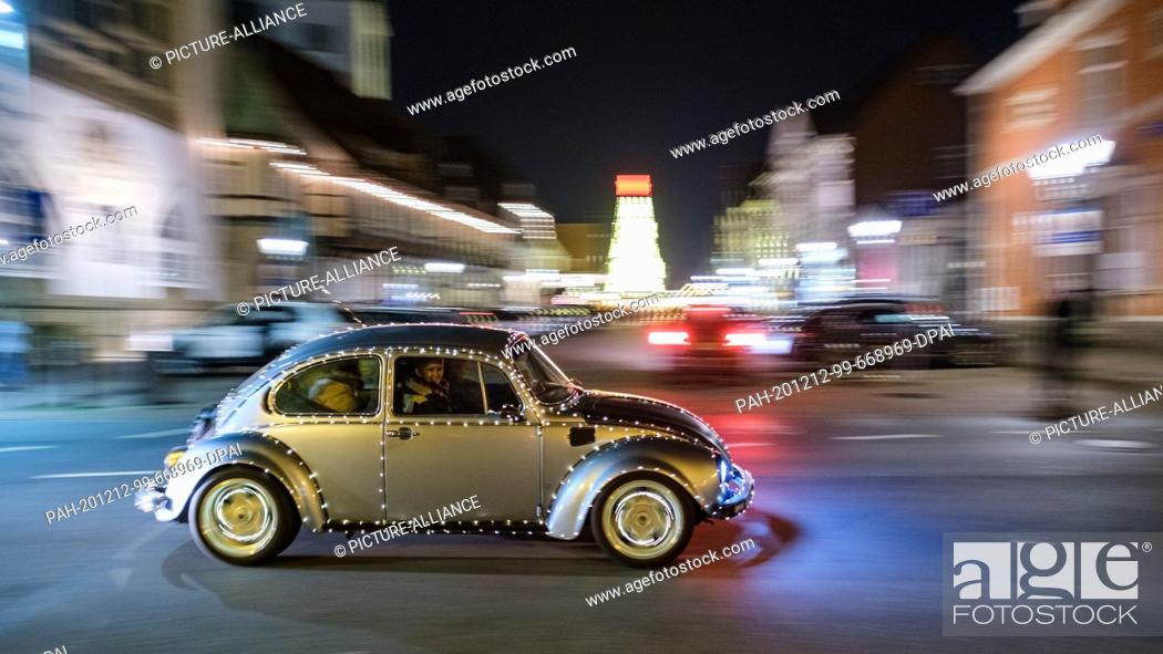 Stock Photo: 12 December 2020, Lower Saxony, Celle: A shining Volkswagen Beetle drives through the city centre of Celle. Since the Christmas markets have been cancelled.