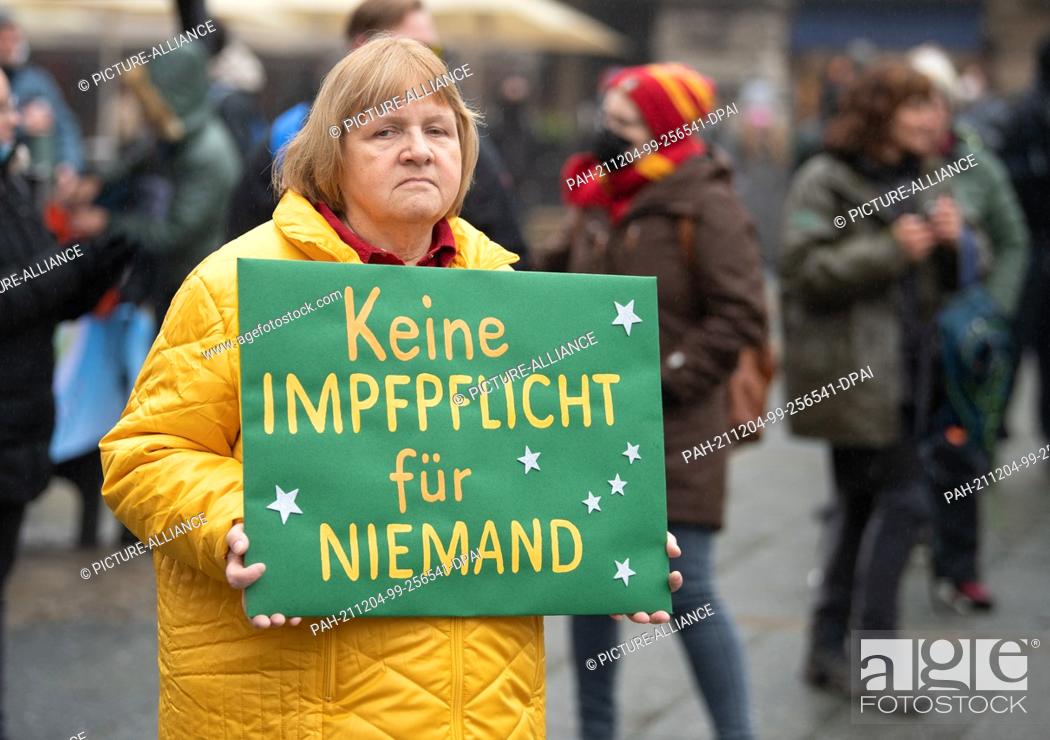 Stock Photo: 04 December 2021, Hessen, Frankfurt/Main: A participant of a demonstration against Corona regulations carries a poster with the inscription ""No compulsory.