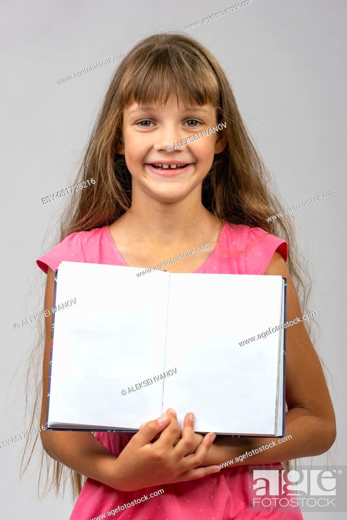 Stock Photo: The girl cheerfully shows the opened empty book in her hands.