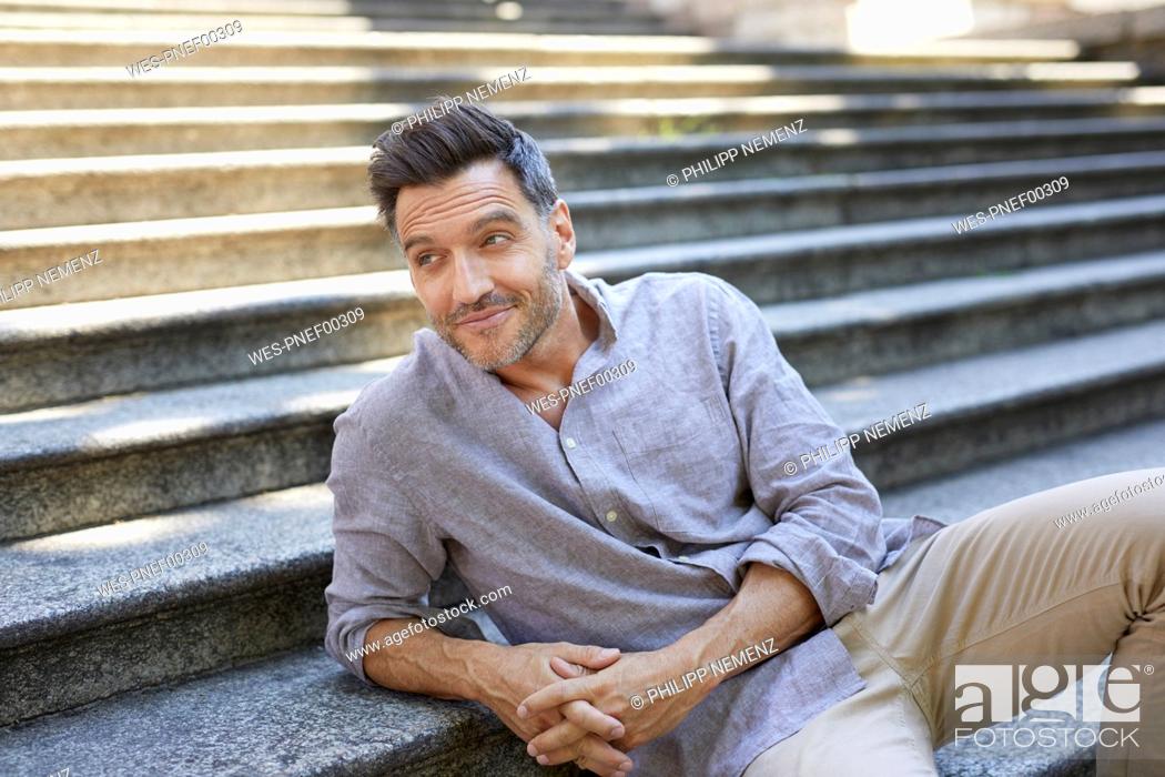 Stock Photo: Portrait of smiling mature man sitting on stairs.