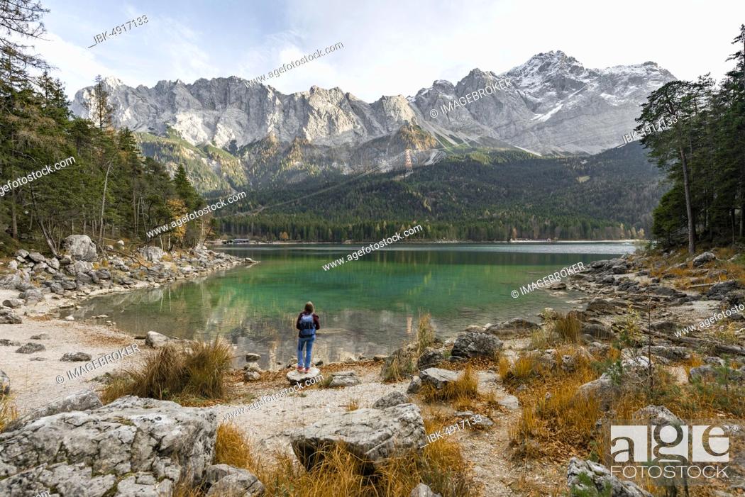 Stock Photo: Female hiker stands on the shore of the Eibsee lake in front of Zugspitze massif with Zugspitze, Wetterstein range, near Grainau, Upper Bavaria, Bavaria.