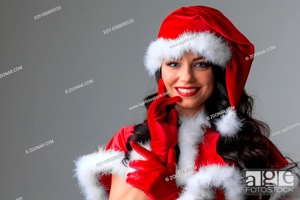 Stock Photo: Pretty Pin-up style Santa girl in red hat on red background.