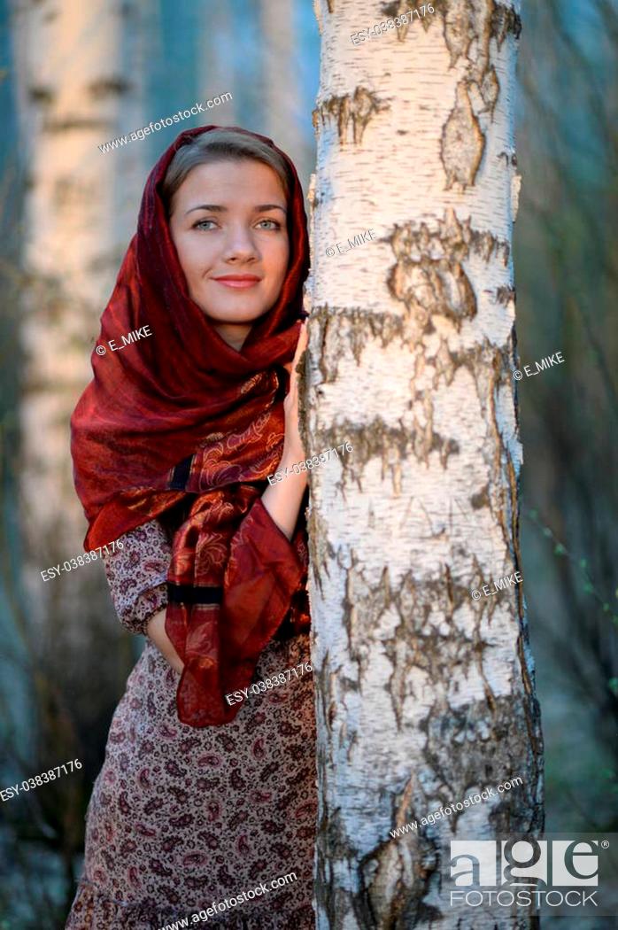 Stock Photo: Russian girl in a scarf in a birch forest, close-up.
