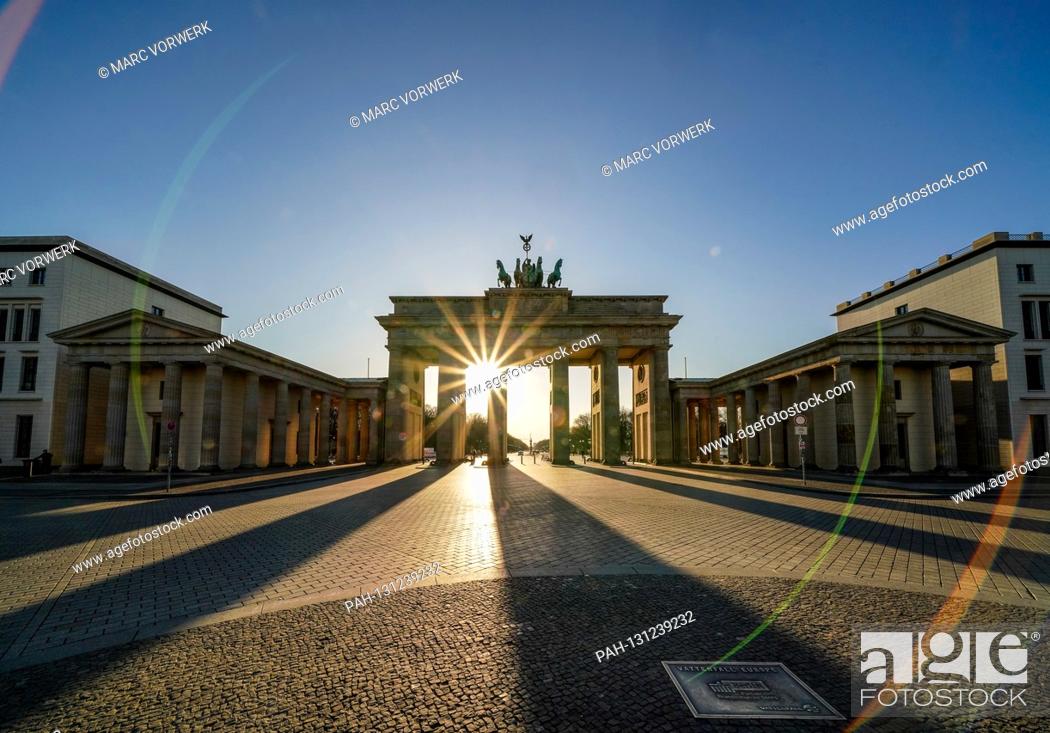 Stock Photo: 23.03.2020, the Brandenburg goal in Berlin on a late spring juice day in the low sun. The sun shines through the prophylaxis and creates a special mood of light.
