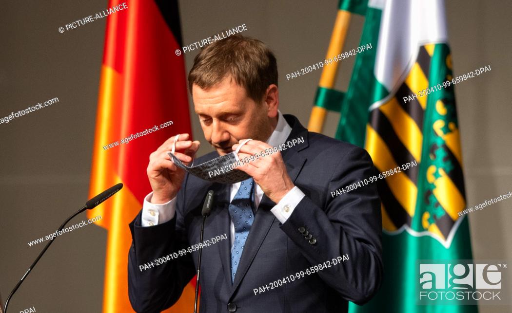 Stock Photo: 09 April 2020, Saxony, Dresden: Michael Kretschmer (CDU), Prime Minister of Saxony, puts on a face mask after his speech during a special session of the Saxon.