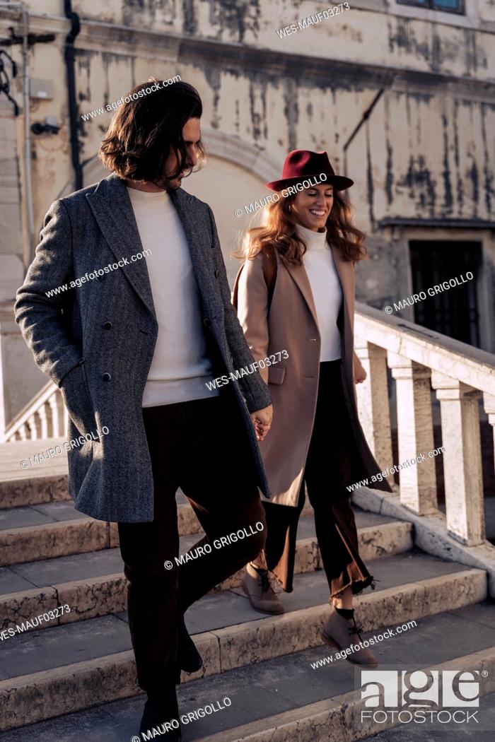 Stock Photo: Young couple walking down a bridge in the city of Venice, Italy.