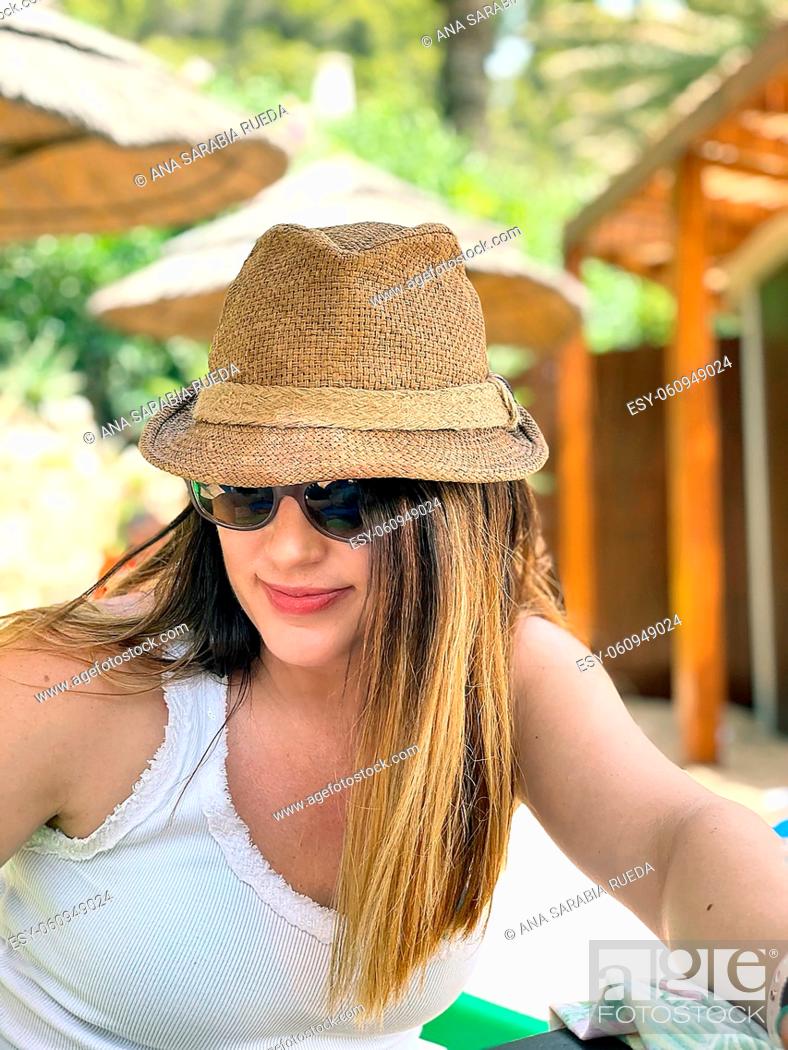 Imagen: Young girl outdoors with straw hat and sunglasses.
