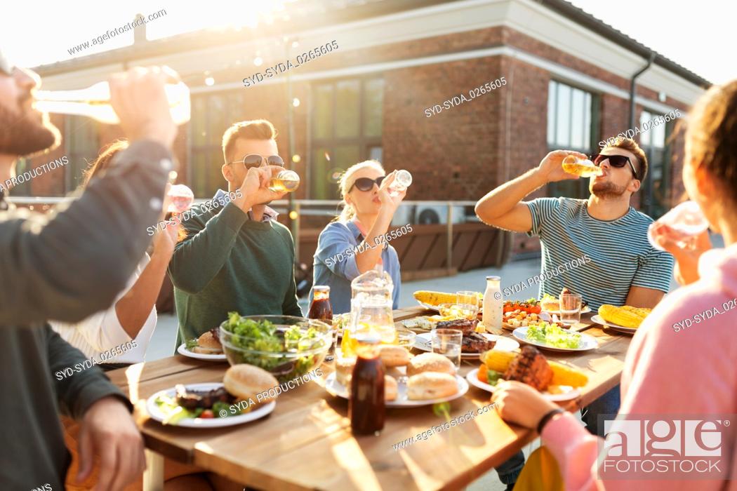 Stock Photo: happy friends with drinks or bbq party on rooftop.
