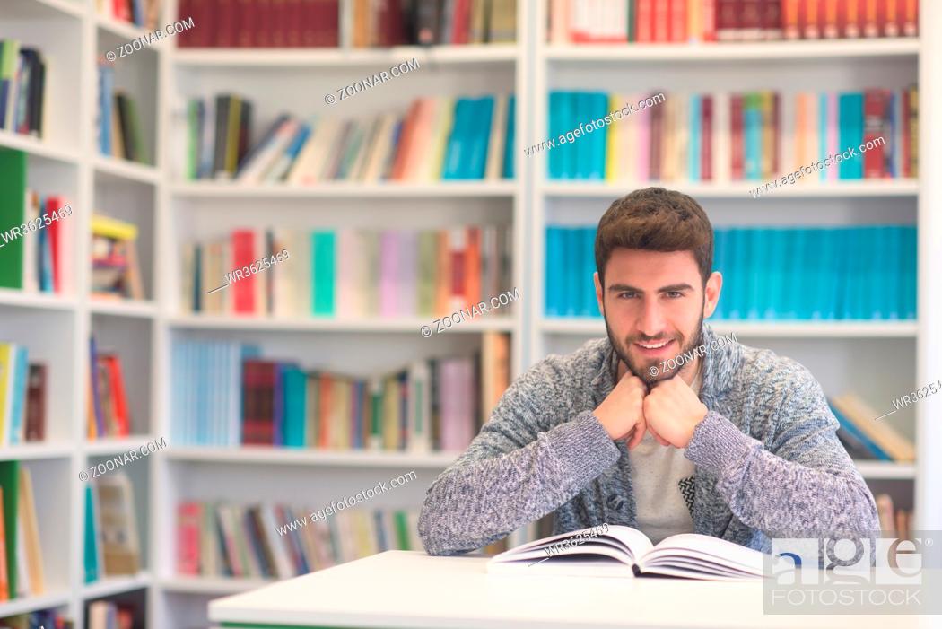 Stock Photo: Portrait of happy student while reading book in school library. Study lessons for exam. Hard worker and persistance concept.