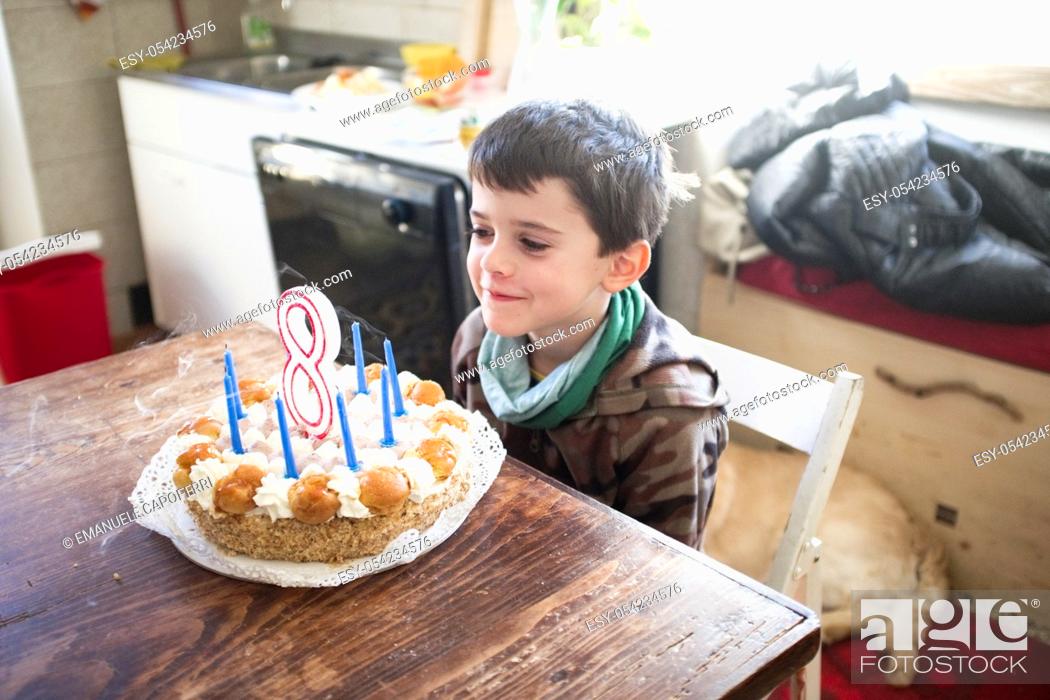 Stock Photo: child turns eight years and blows out the candles of the cake.
