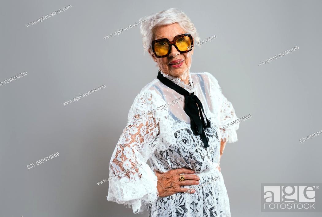 Stock Photo: beautiful and elegant old influencer woman. Cool grandmother posing in studio wearing fashionable clothes. Happy senior lady celebrating and making party.