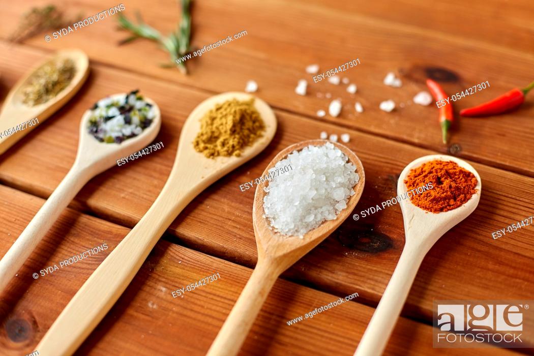 Stock Photo: spoons with spices and salt on wooden table.