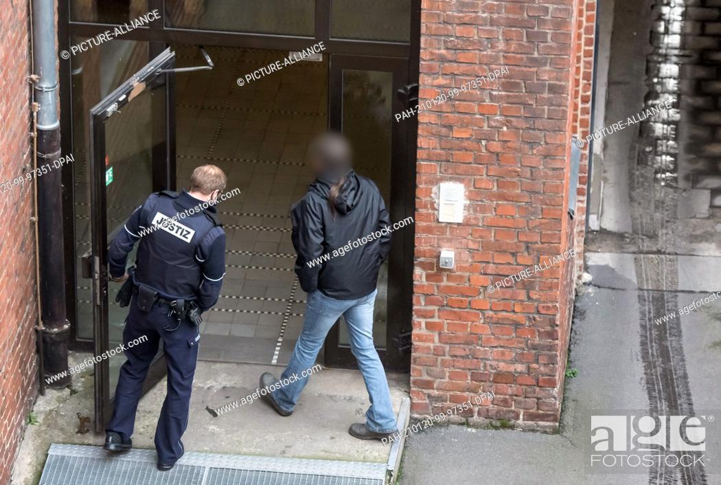 Stock Photo: 20 January 2021, North Rhine-Westphalia, Dortmund: The defendant enters the district court through a side entrance (photographed through a window pane).
