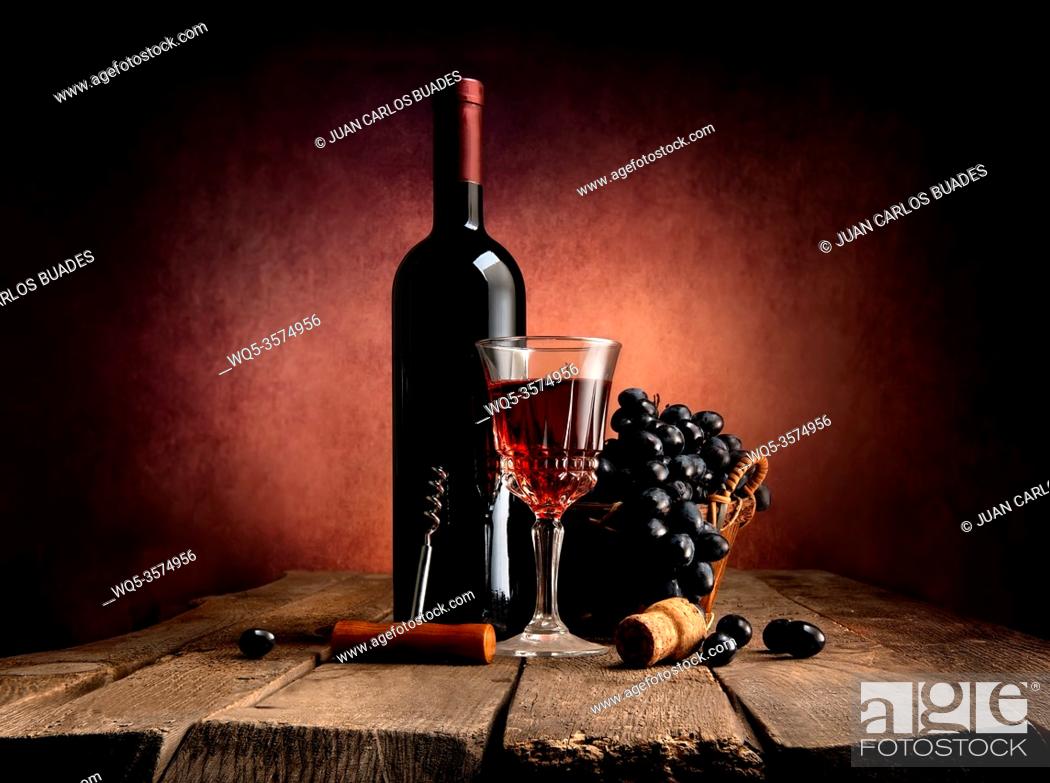 Imagen: Grape in basket with wine on a wooden table.