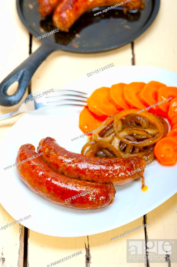 Stock Photo: beef sausages cooked on iron skillet with carrot and onion.