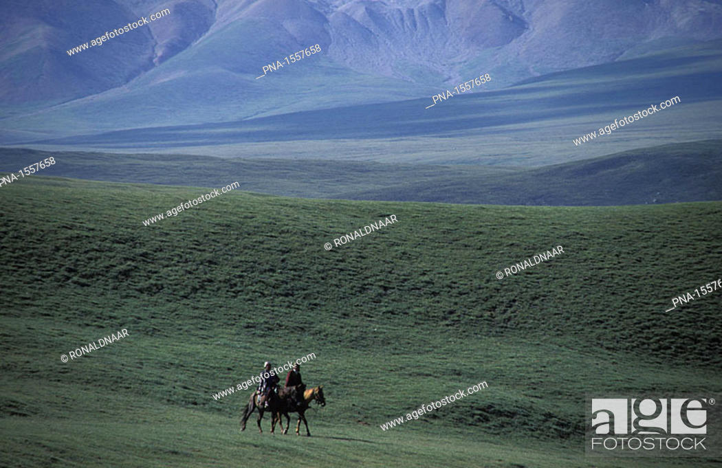 Stock Photo: Two Kirghiz herdsmen driving their horses through the Tien Shan mountains, Kirghizistan.