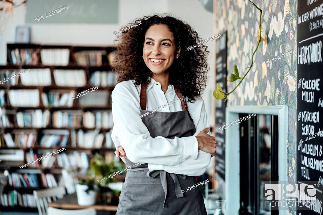 Stock Photo: Young entrepreneur wearing apron looking away while standing at cafe.