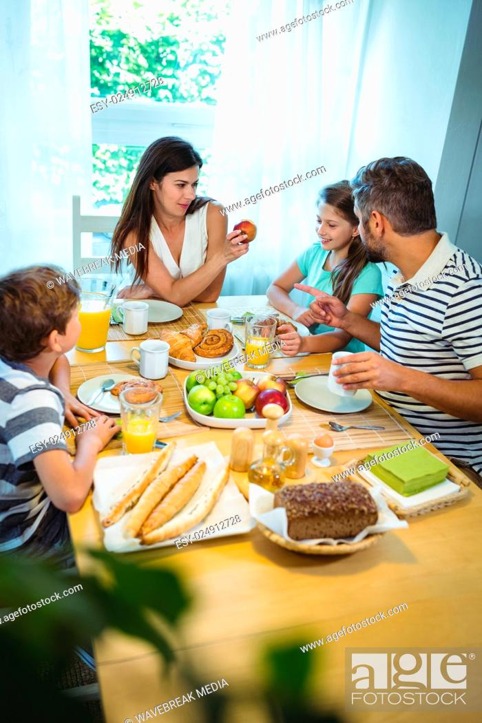 Stock Photo: Happy family talking to each other while having breakfast together.