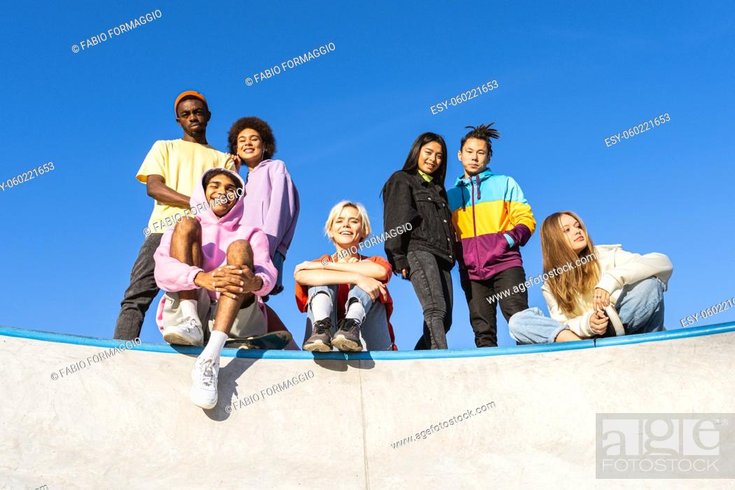 Stock Photo: Multicultural group of young friends bonding outdoors and having fun - Stylish cool teens gathering at urban skate park.