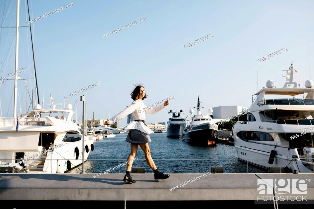 Imagen: Pretty businesswoman walking at the marina after work, smiling.