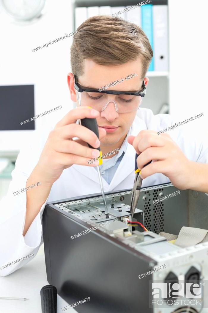 Stock Photo: Computer engineer working on broken device with screwdriver.