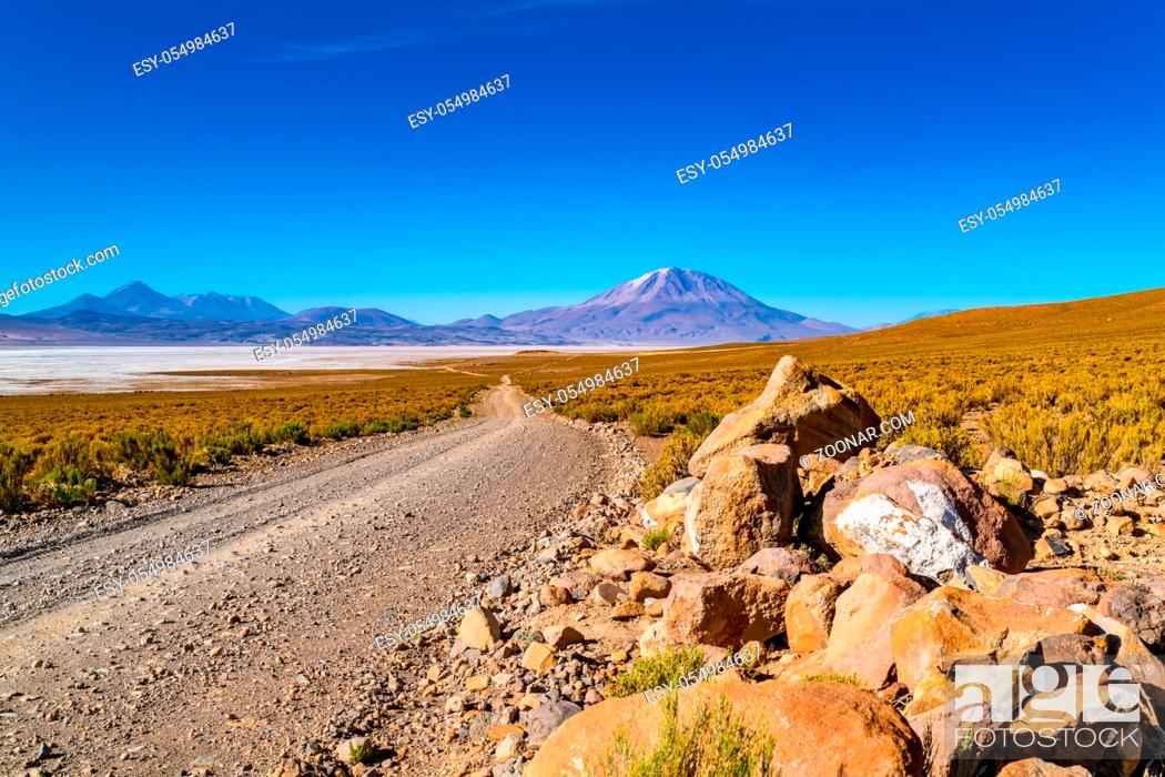 Stock Photo: View of Salar de Uyuni with the dormant volcano and a dirty road in Bolivia.