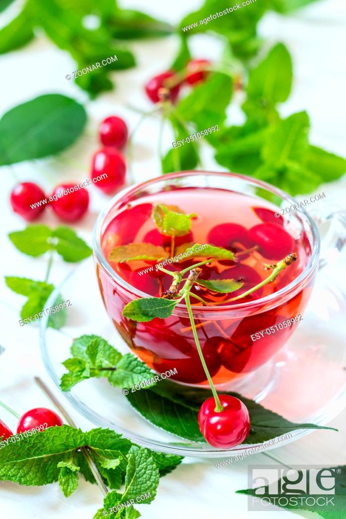 Stock Photo: Fresh fruit cherry drink in transparent glass cup surrounded by cherries on the white wooden background.