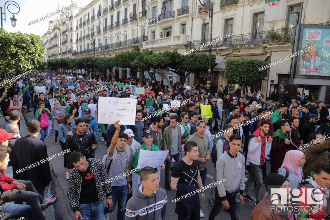 Stock Photo: 12 March 2019, Algeria, Algiers: Algerian students march with placards and flags during a protest one day after President Abdelaziz Bouteflika announced his.