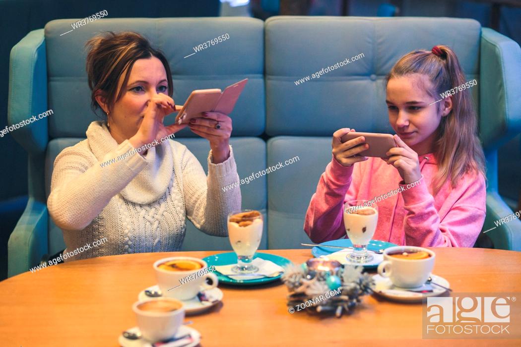 Stock Photo: Women taking photos of dessert in coffee shop, using smartphone camera. Candid people, real moments, authentic situations.