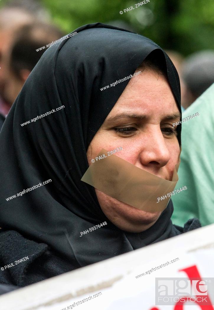 Stock Photo: A woman with tape over her mouth outside a police station, Berlin, Germany 21 June 2015. A protest of about 60 people calling for the release of Al Jazeera.