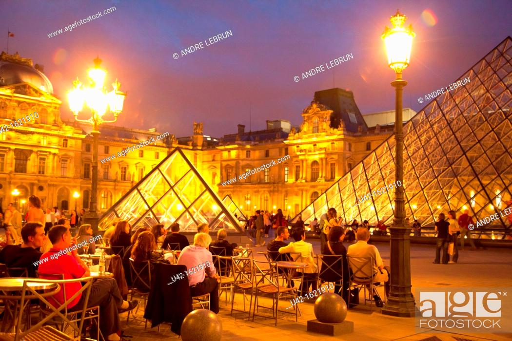 Stock Photo: Sitting in a cafe in Cour Napoleon by the Pyramide and Musee du Louvre in Paris at night, France.