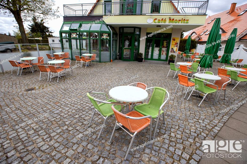Stock Photo: 06 May 2021, Mecklenburg-Western Pomerania, Koserow: Empty tables of guests stand in front of a café in the city centre. The holiday industry and the.