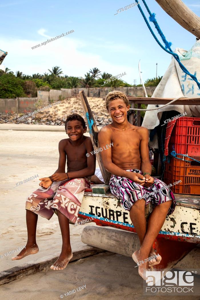 Stock Photo: Young local boys sitting on a Jangada fishing boat, Iguape, Fortaleza district, Brazil.