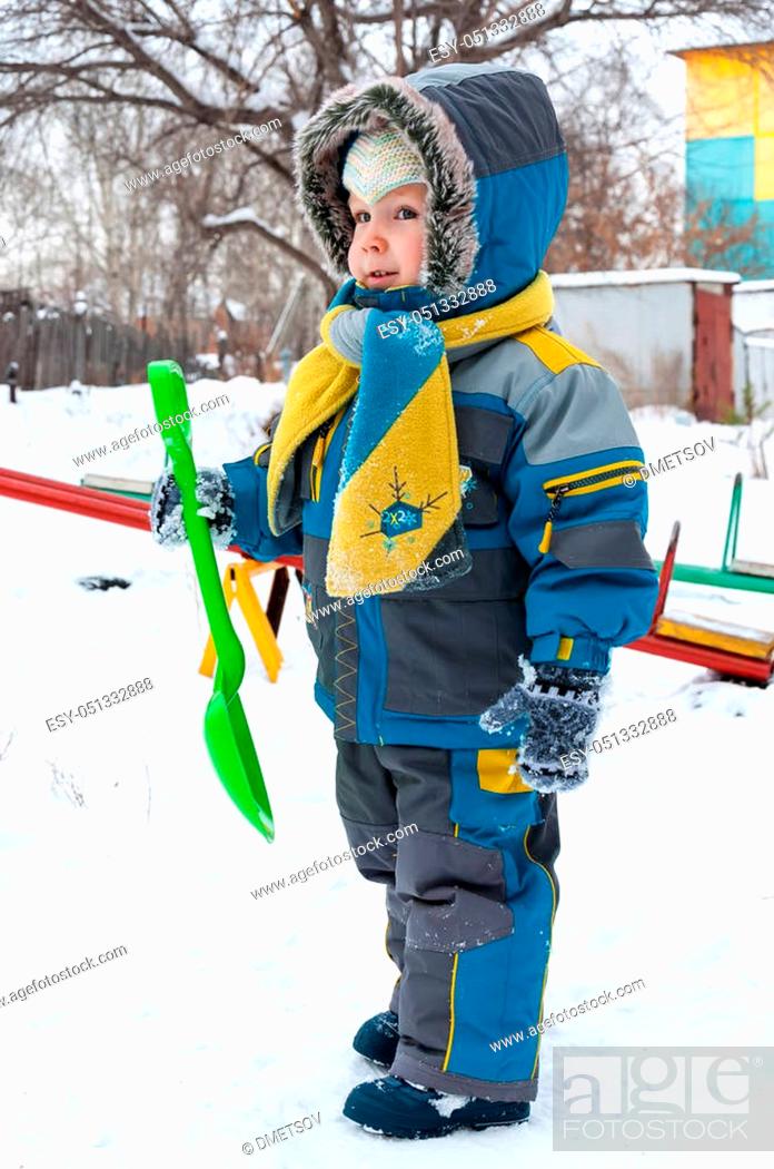 Stock Photo: Little boy playing with snow and spade. Baby playing with snow in winter outdoors. Winter vacations. Children's winter games outdoors.