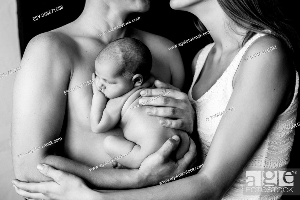Stock Photo: Mother and father holding their newborn baby at a newborn photoshoot. High quality photo.