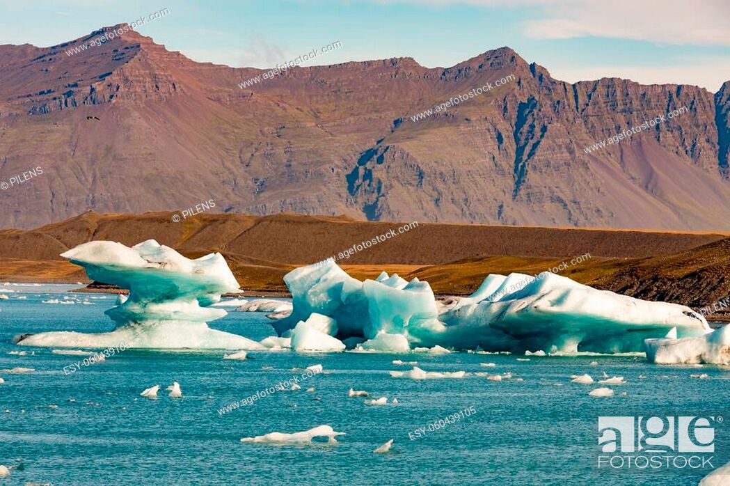 Stock Photo: Glacial icebergs floating in Jokulsarlon glacier lagoon fed by Vatnajokull icefield and framed by rugged barren mountain ranges in Vatnajokull National Park.