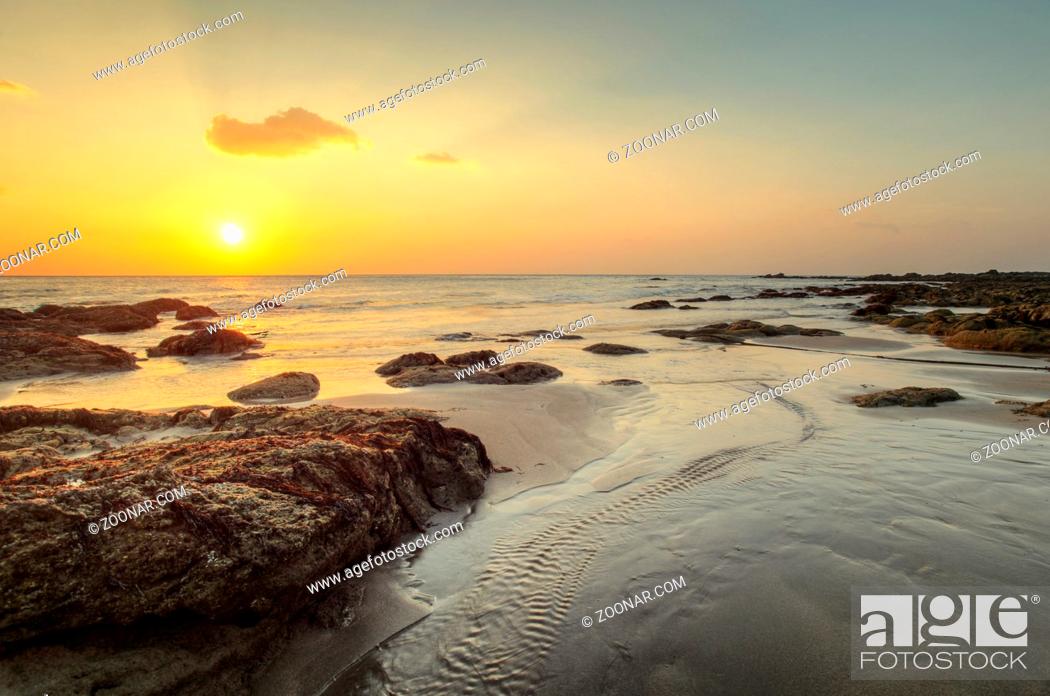 Stock Photo: Beach in golden sunset light during low tide showing stream of water and rocks covered with sea algae. Kantiang Bay, Ko Lanta, Thailand.