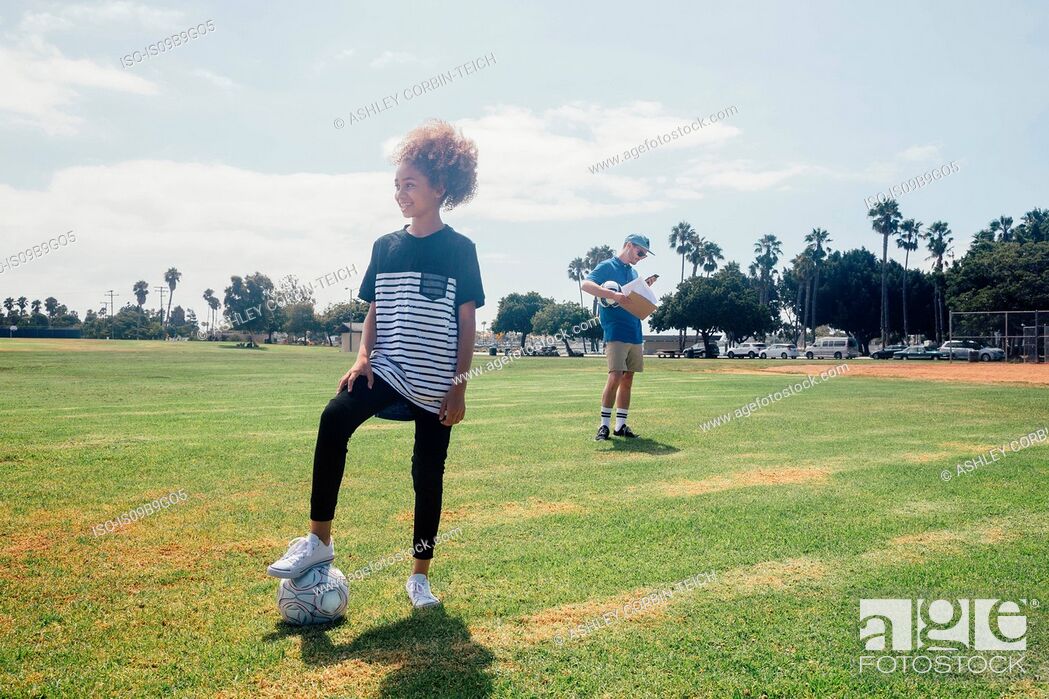 Stock Photo: Portrait of schoolgirl with foot on soccer ball on school sports field.