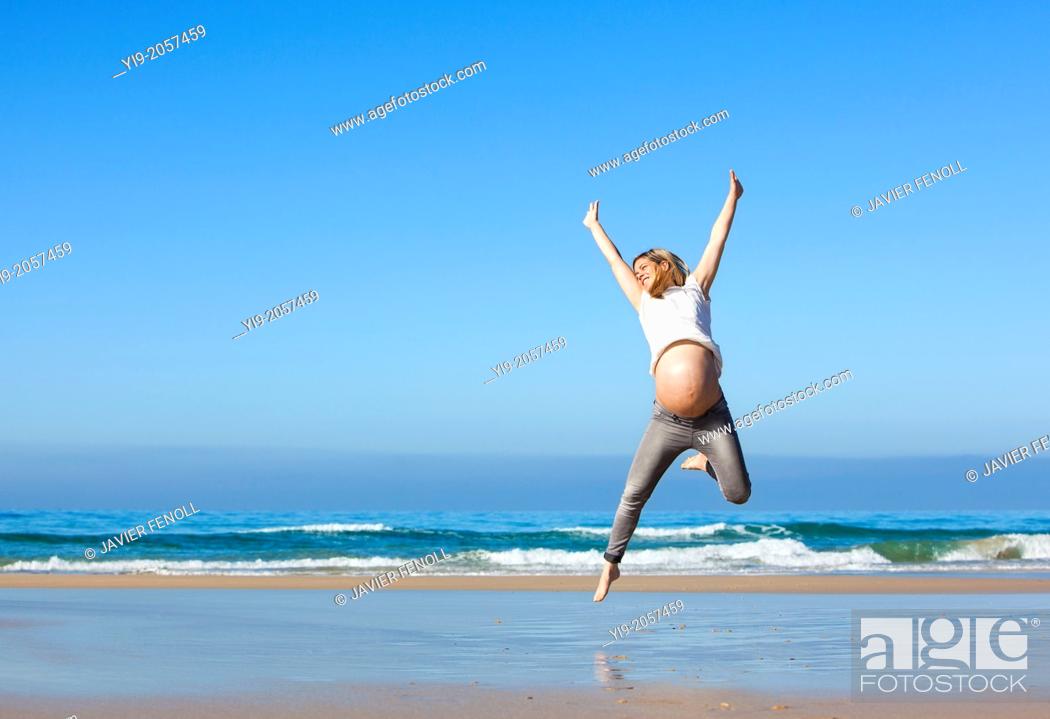Stock Photo: pregnant woman jumping on the beach.
