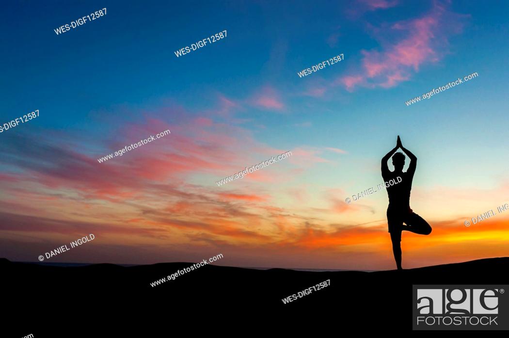 Stock Photo: Silhouette of man doing yoga at sunset, Gran Canaria, Spain.