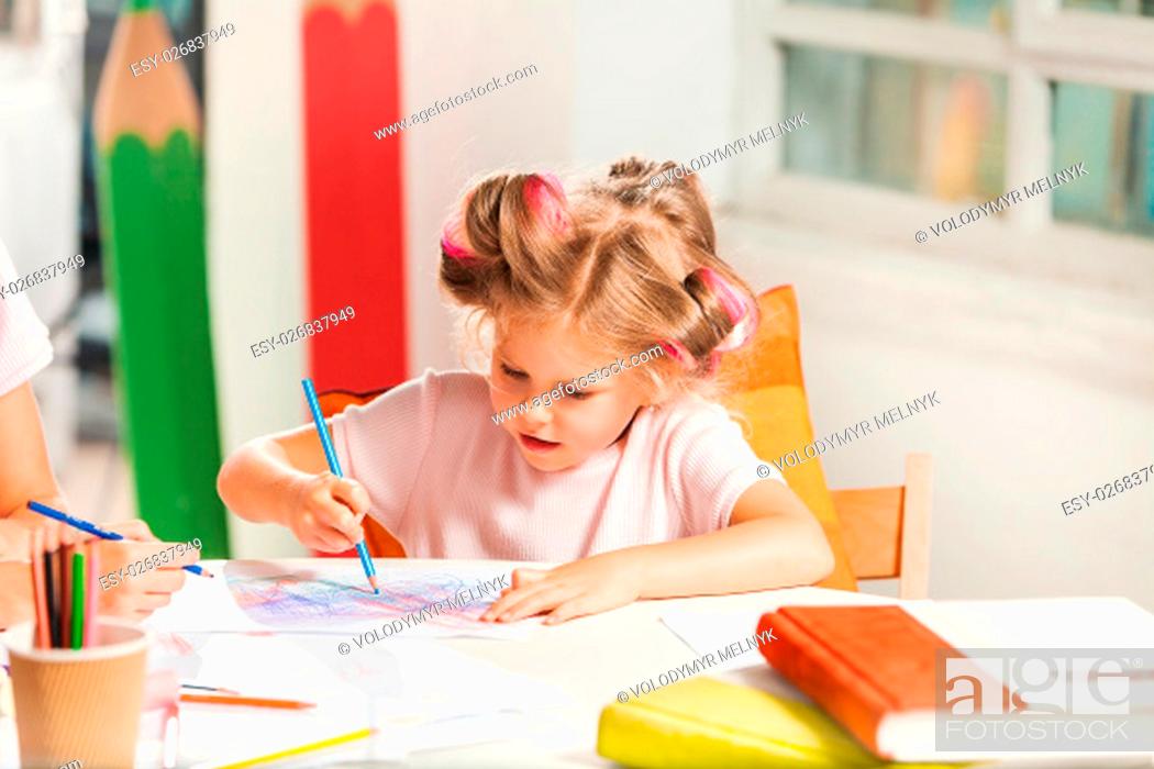 Stock Photo: The young mother and her daughter drawing with pencils at home.