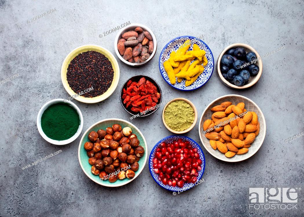 Stock Photo: Set of different superfoods in bowls on stone gray background: spirulina, goji berry, cocoa, matcha green tea powder, quinoa, chia seeds, blueberries.