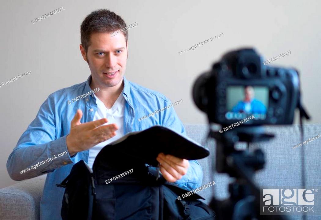 Stock Photo: Handsome man making video blog about travel backpack.