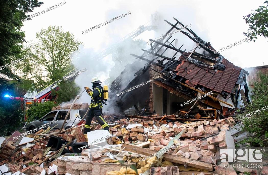 Stock Photo: 23 May 2019, Schleswig-Holstein, Wohltorf: A firefighter is standing in the ruins of a house that was destroyed in a fire.