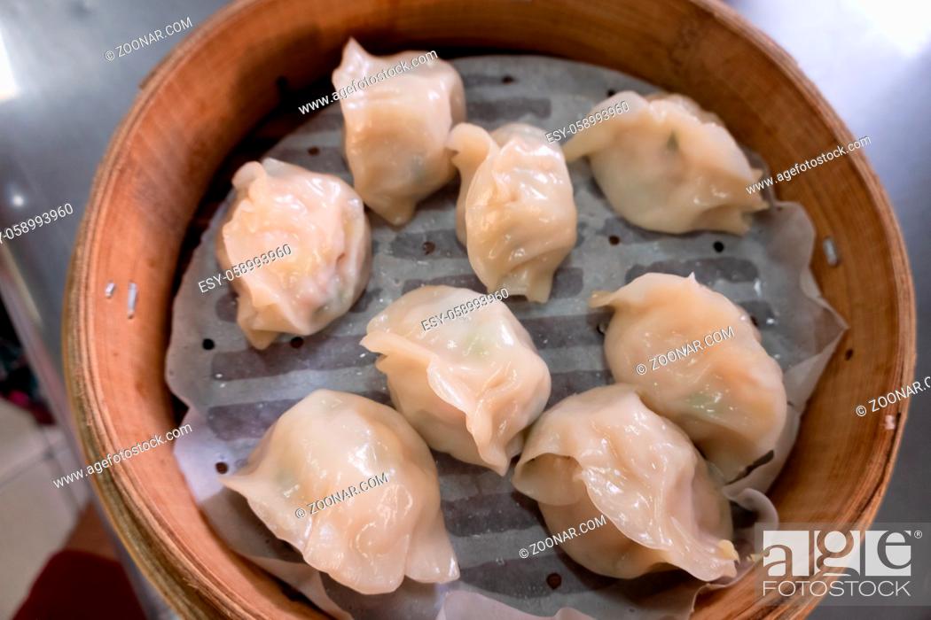 Stock Photo: Chinese steamed jiaozi in a bamboo steamer on a table in Taiwan.