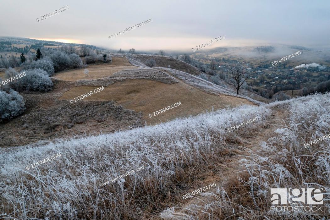 Stock Photo: Winter coming. Picturesque pre sunrise scene above late autumn mountain countryside with hoarfrost on grasses, trees, slopes.