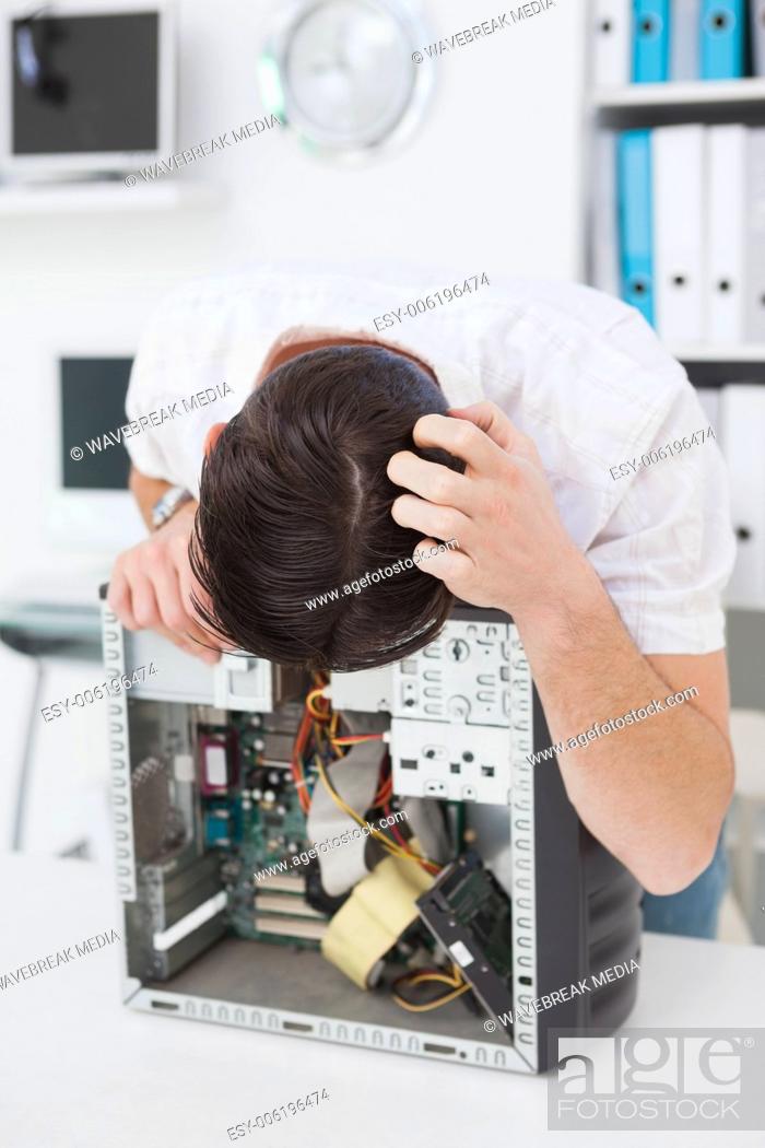 Stock Photo: Computer engineer looking at broken device.