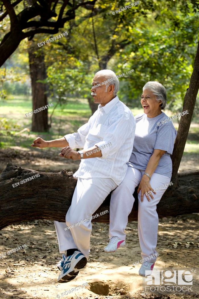 Stock Photo: Playful couple having fun at park while sitting on tree trunk.